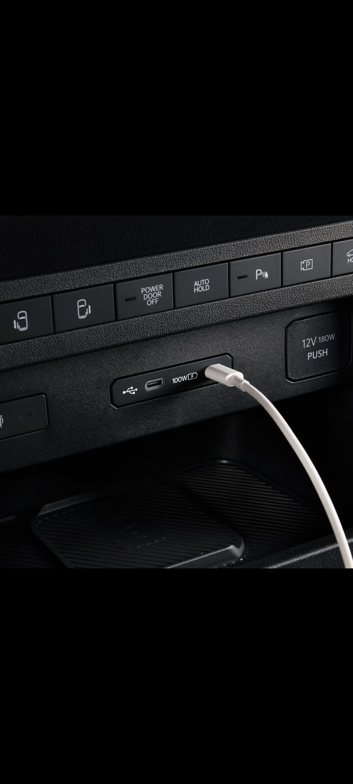 Nahaufnahme des USB-Anschlusses im Armaturenbrett des Kia PV5 Passenger mit angeschlossenem Kabel.